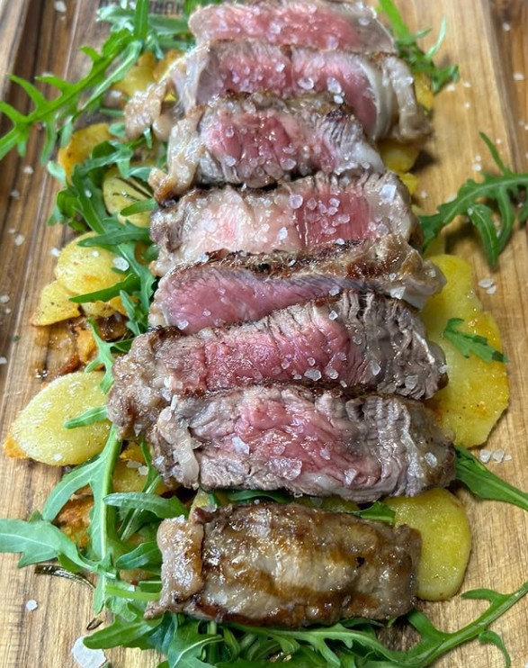 Rosa gebratenes Rindfleisch mit Kartoffeln und Rucola